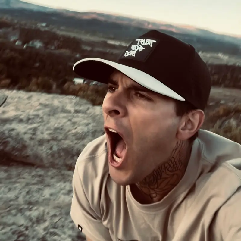Wyatt Coats speaking outdoors in his Trust God cap